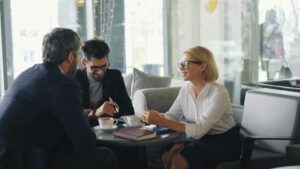 Three professionals engaged in a business meeting at a cafe.