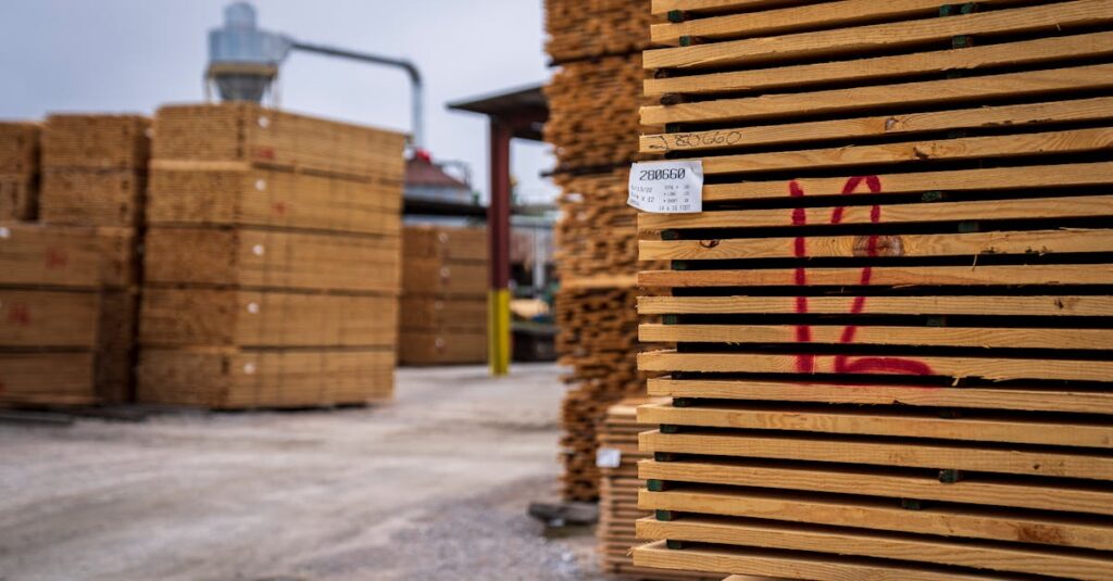 pexels-photo-12278592-12278592 Wooden planks neatly stacked in an outdoor lumber yard, ready for shipment.